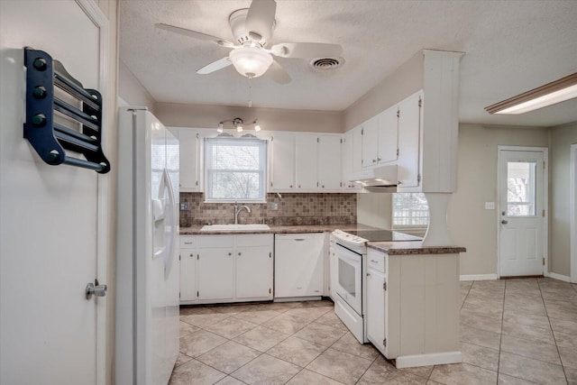 kitchen with sink, white appliances, light tile patterned floors, tasteful backsplash, and white cabinets