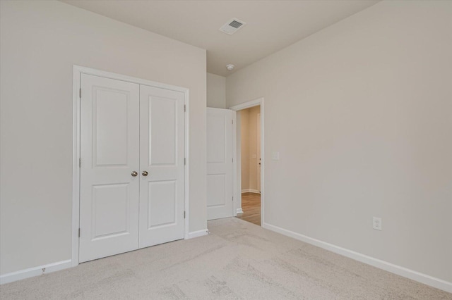 unfurnished bedroom with light carpet and a closet