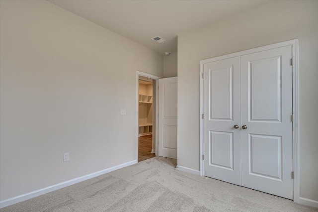 unfurnished bedroom with light carpet and a closet