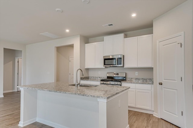 kitchen featuring sink, stainless steel appliances, light stone countertops, a kitchen island with sink, and white cabinets