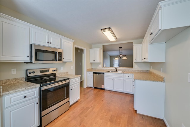 kitchen featuring white cabinetry, appliances with stainless steel finishes, light wood-style flooring, and a sink