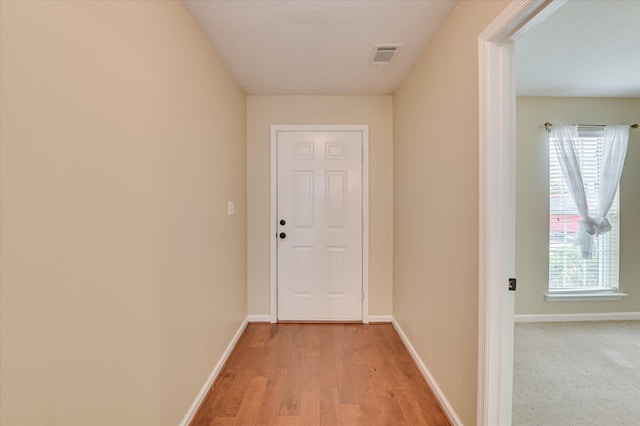 corridor with visible vents, light wood finished floors, and baseboards