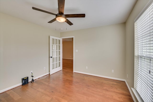 unfurnished room with ceiling fan, baseboards, wood finished floors, and plenty of natural light