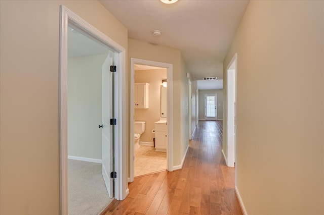 corridor featuring visible vents, light wood-type flooring, and baseboards