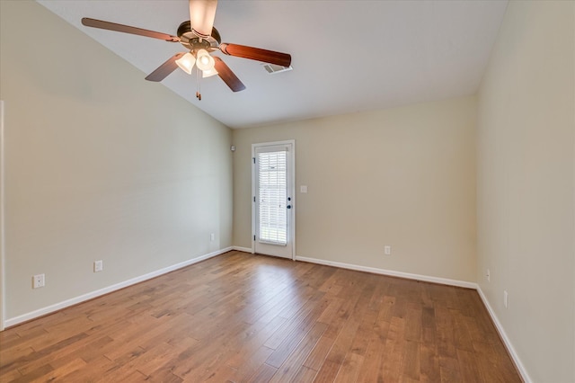 empty room featuring lofted ceiling, wood finished floors, a ceiling fan, and baseboards