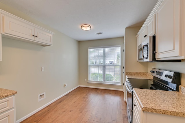 kitchen featuring light wood finished floors, visible vents, stainless steel appliances, and baseboards