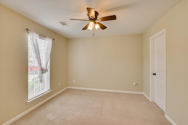 empty room featuring a wealth of natural light, visible vents, and light carpet