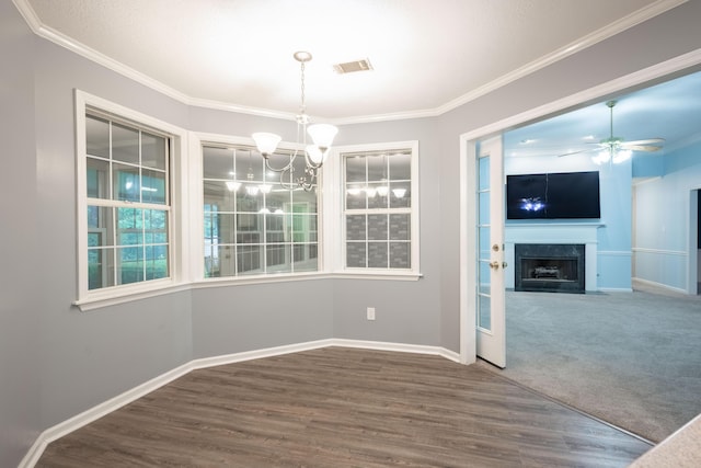 unfurnished dining area with ceiling fan with notable chandelier, dark wood-type flooring, and crown molding