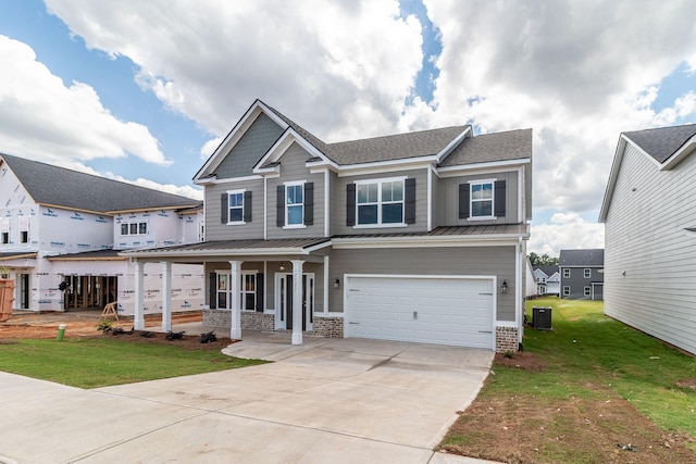 craftsman-style home with covered porch, central air condition unit, a garage, and a front yard