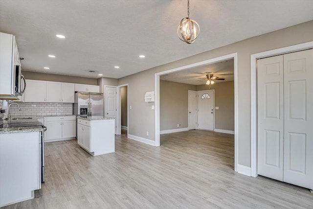 kitchen with a kitchen island, white cabinets, backsplash, hanging light fixtures, and stainless steel appliances