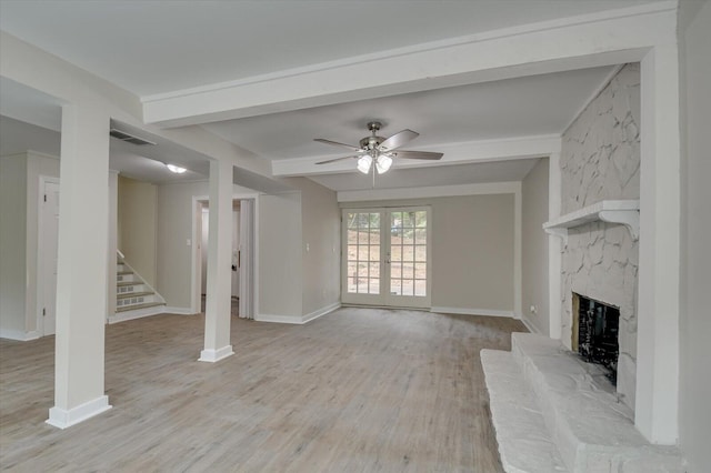 unfurnished living room featuring ceiling fan, light wood-style floors, a fireplace, beamed ceiling, and stairs