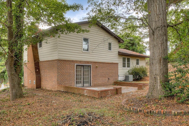 rear view of house with brick siding, a patio area, and central AC unit
