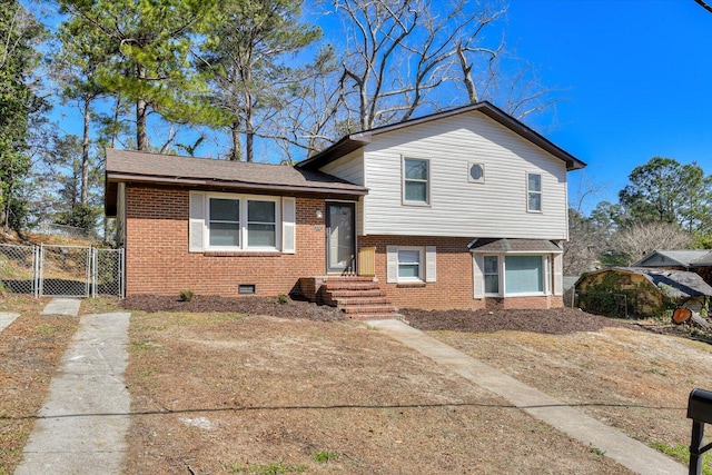 tri-level home featuring brick siding, fence, and a gate