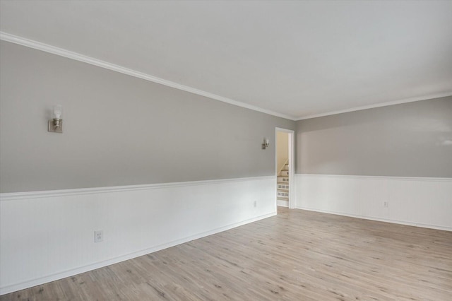 empty room featuring ornamental molding, a wainscoted wall, stairway, wood finished floors, and baseboards
