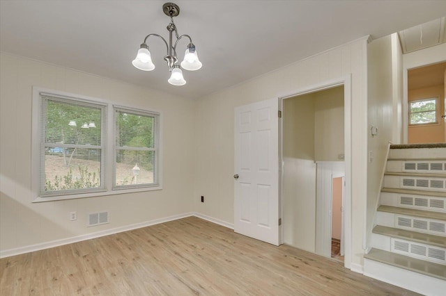 spare room featuring visible vents, baseboards, a notable chandelier, and light wood-style floors