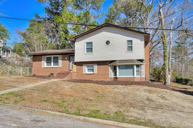 tri-level home featuring fence and brick siding