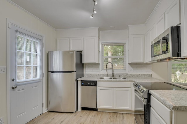 kitchen with appliances with stainless steel finishes, light countertops, white cabinets, decorative backsplash, and a sink