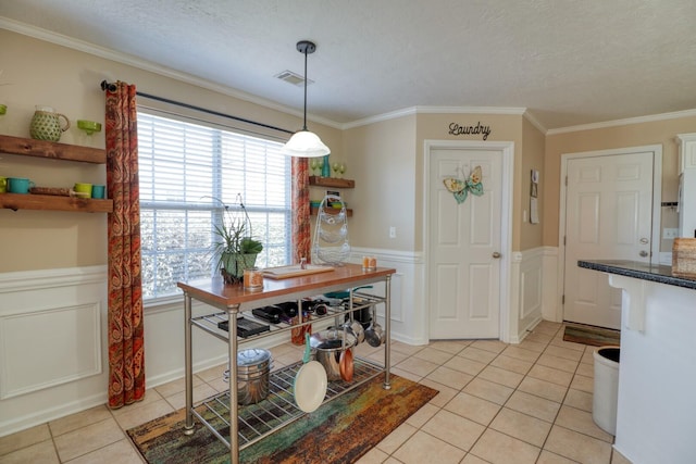 tiled dining room with ornamental molding and a textured ceiling