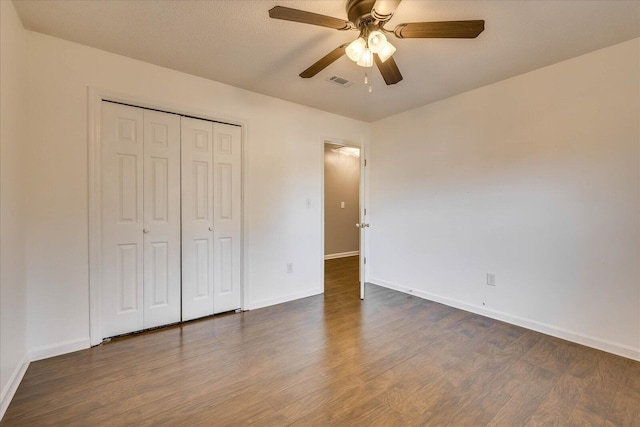 unfurnished bedroom featuring a closet, ceiling fan, and dark wood-type flooring