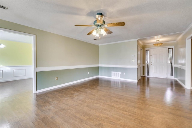 unfurnished room with ceiling fan, wood-type flooring, a textured ceiling, and ornamental molding