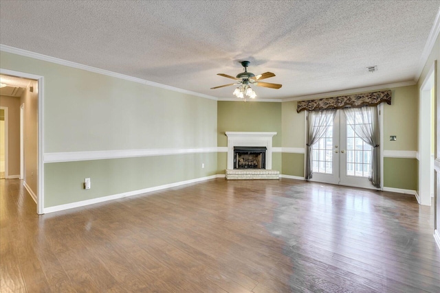 unfurnished living room with ceiling fan, ornamental molding, a fireplace, and french doors