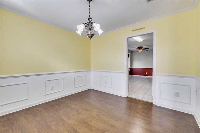 spare room featuring ceiling fan with notable chandelier, dark hardwood / wood-style flooring, ornamental molding, and a textured ceiling