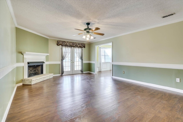 unfurnished living room with a brick fireplace, ceiling fan, crown molding, and french doors