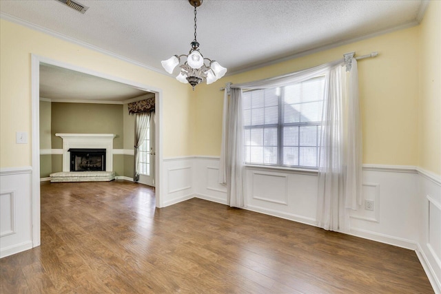 unfurnished dining area featuring crown molding, hardwood / wood-style flooring, a textured ceiling, and a notable chandelier