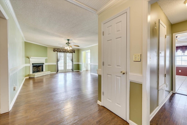 unfurnished living room with ceiling fan, wood-type flooring, ornamental molding, and french doors