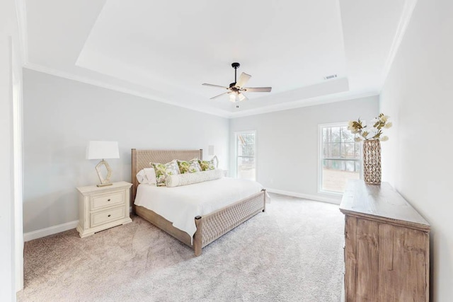 carpeted bedroom featuring a raised ceiling, ceiling fan, and crown molding