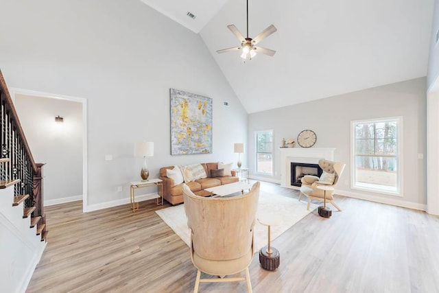 living room featuring high vaulted ceiling, light hardwood / wood-style flooring, and a wealth of natural light