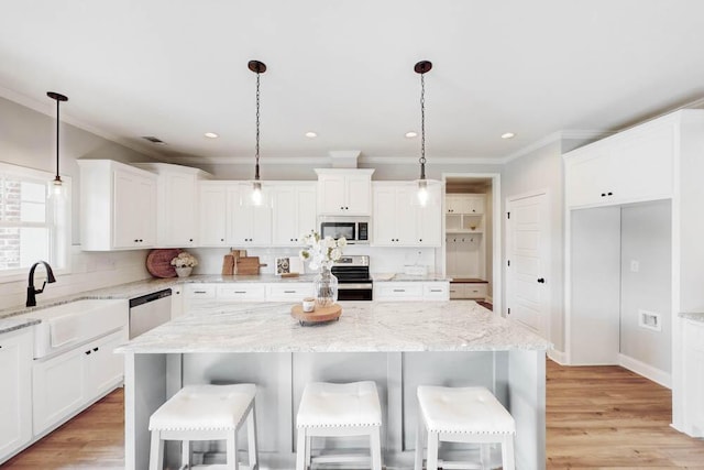 kitchen featuring stainless steel appliances, decorative light fixtures, a center island, and light stone counters