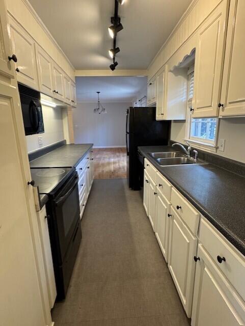 kitchen featuring dark countertops, white cabinets, a sink, and black appliances