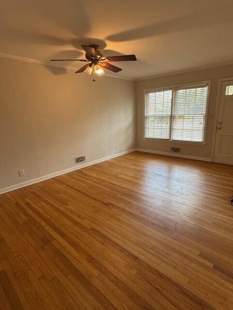 unfurnished room with ornamental molding, wood finished floors, and baseboards