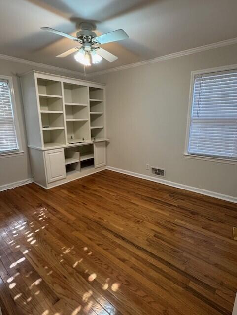 unfurnished bedroom featuring dark wood finished floors, visible vents, and crown molding