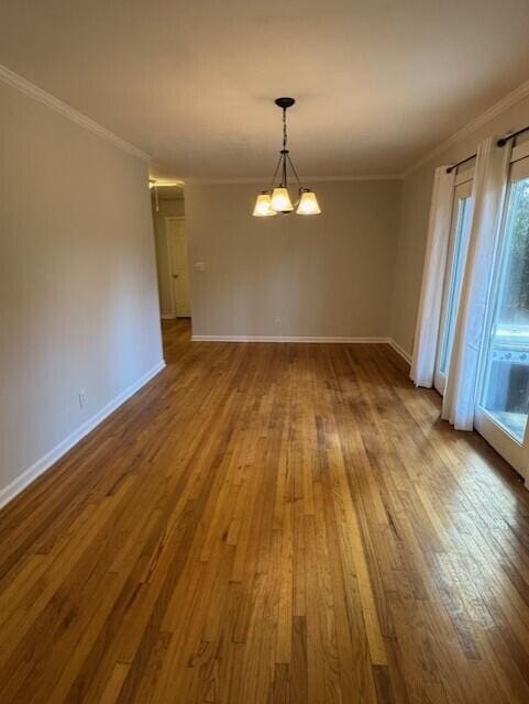 spare room with a notable chandelier, baseboards, wood finished floors, and crown molding