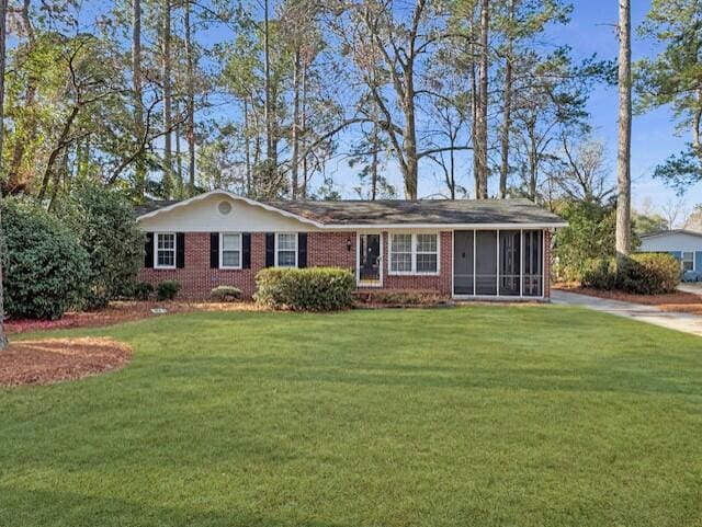 ranch-style home featuring a sunroom, a front lawn, and brick siding