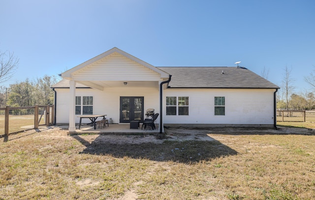 rear view of property featuring a yard, a patio, roof with shingles, and fence