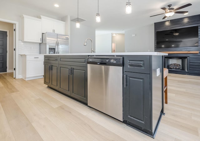 kitchen with tasteful backsplash, light wood-style floors, appliances with stainless steel finishes, white cabinets, and light countertops