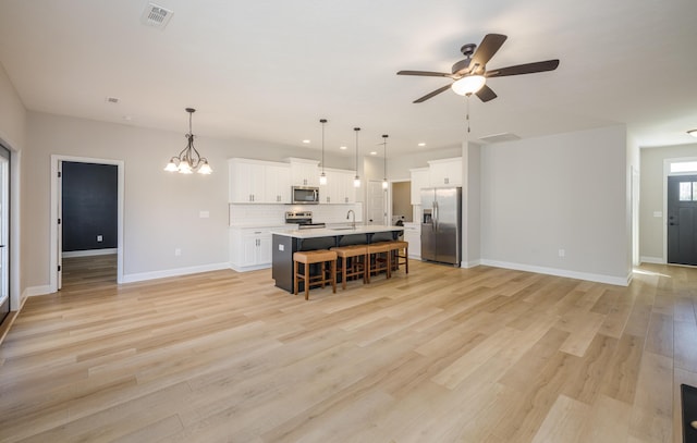 kitchen featuring visible vents, open floor plan, a kitchen bar, decorative backsplash, and stainless steel appliances