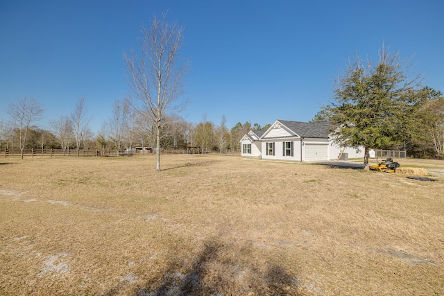 view of yard featuring an attached garage and fence