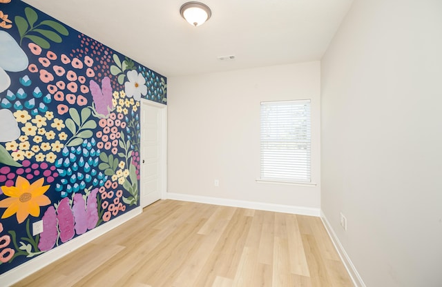 empty room featuring visible vents, baseboards, and wood finished floors