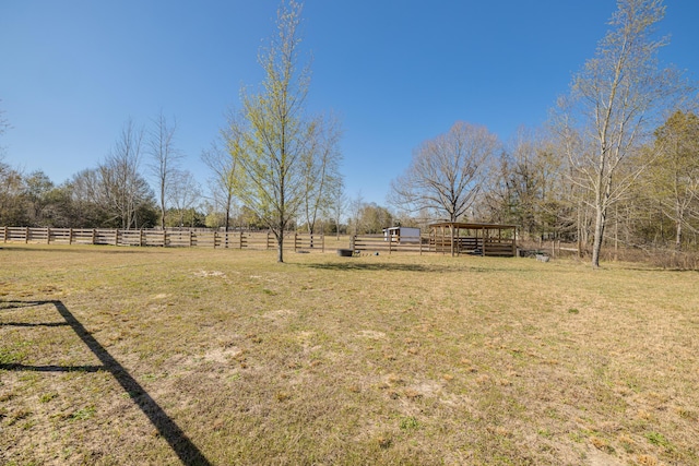 view of yard featuring an outdoor structure, a rural view, and fence