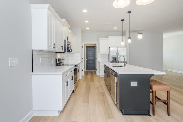 kitchen featuring white cabinets, appliances with stainless steel finishes, a kitchen breakfast bar, and a sink