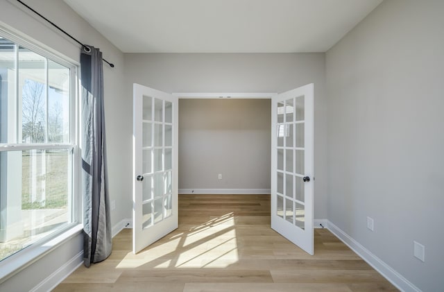 unfurnished room with light wood-type flooring, french doors, and baseboards