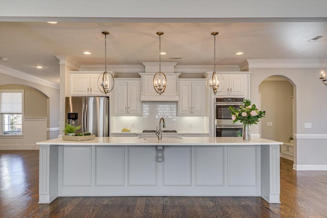 kitchen with pendant lighting, stainless steel appliances, sink, and a large island with sink