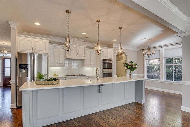 kitchen with sink, an inviting chandelier, stainless steel appliances, a spacious island, and decorative light fixtures