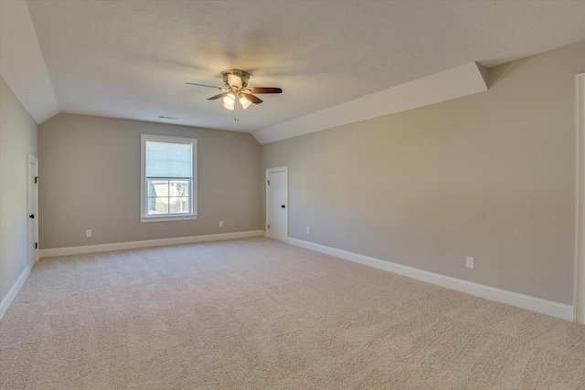 spare room with vaulted ceiling, light colored carpet, ceiling fan, and a textured ceiling