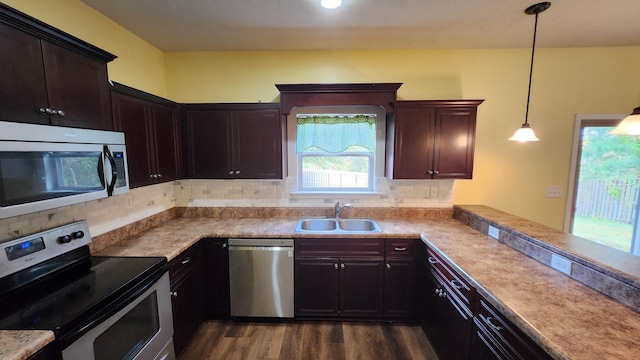 kitchen featuring sink, stainless steel appliances, kitchen peninsula, pendant lighting, and decorative backsplash
