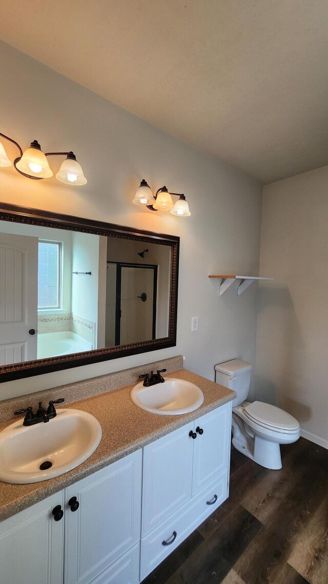 full bathroom with hardwood / wood-style floors, vanity, shower with separate bathtub, and toilet